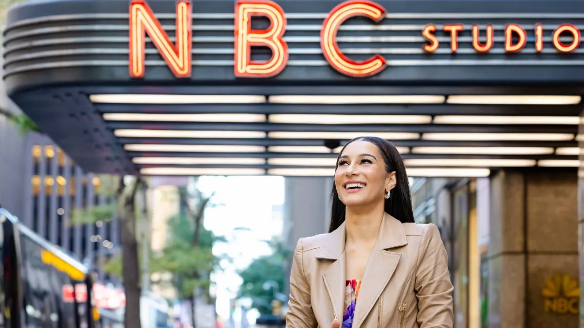 A person smiling under the NBC Studios marquee with red neon lettering.
