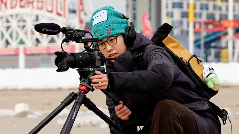 A student operating a professional camera at Coney Island in the wintertime. 