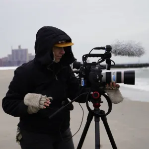 Student filming on the beach at Coney Island. 