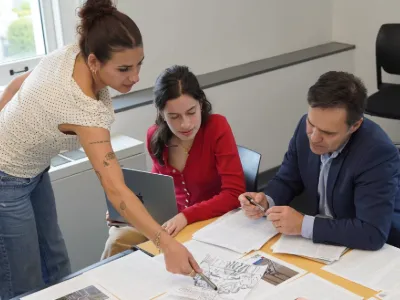 Students work with a professor on magazine layout for class. 