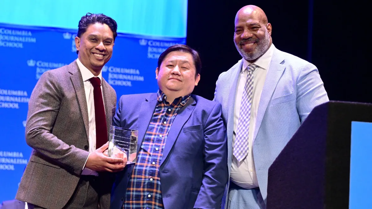 Chao Xiong (center), director of editorial for 2026 Sahan Journal, recipient of the 2026 Columbia Journalism Awards, before delivering the keynote address at graduation, alongside Vanan Murugesan (left), executive director of the publication, and Dean Jelani Cobb (right).