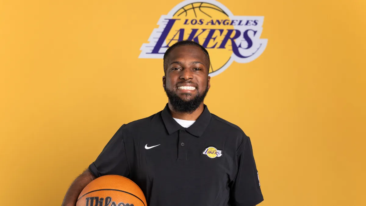 Photo of George Hamilton III in front of the Los Angeles Lakers logo. 