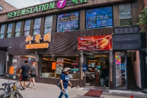 Street-level storefront with colorful signage and pedestrians walking along the sidewalk.