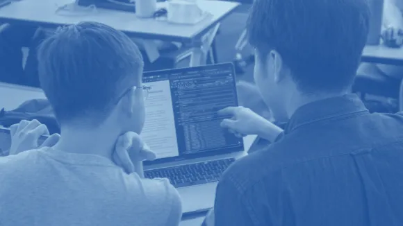 Two students coding on a computer. 