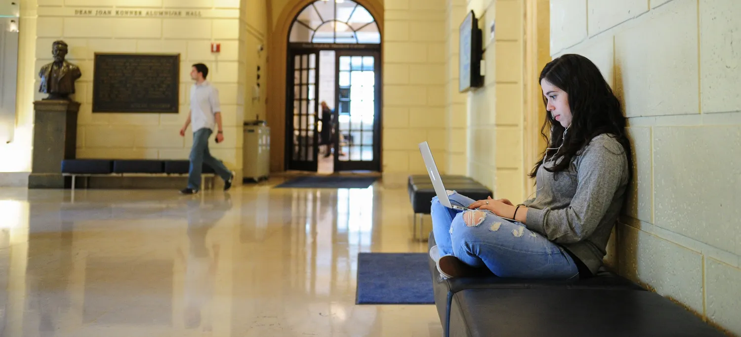Student sitting in the main lobby of Pulitzer Hall