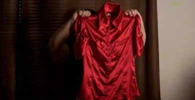 Photo of a woman holding a red dress that obscures her face.